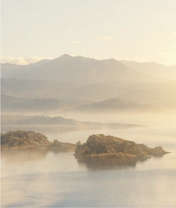 Soft morning light over a river and distant mountains. An open horizon.